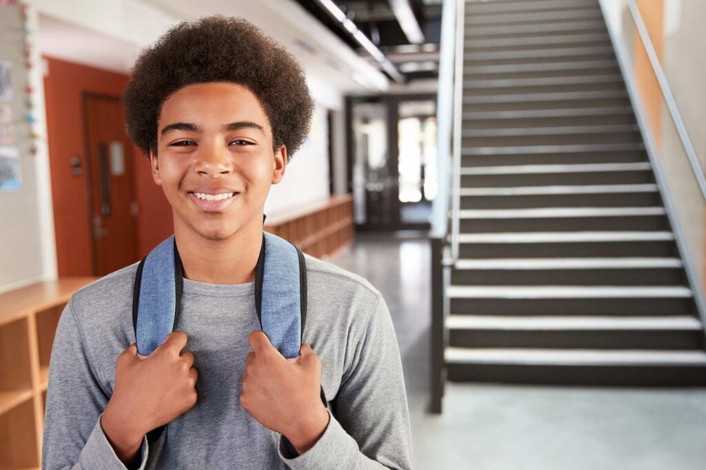 Image of a boy standing in a school with his backpack on