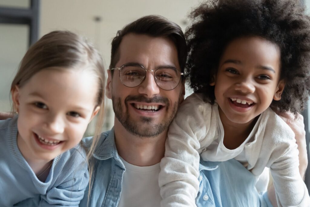 Image of two girls playing with their dad on his shoulders