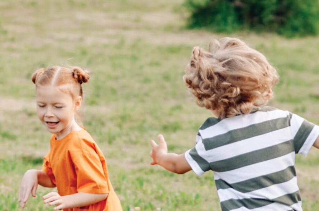 Image of a boy and a girl playing in a field