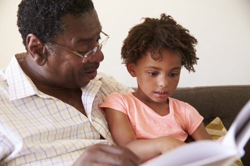 Image of a girl reading a book with her grandfather