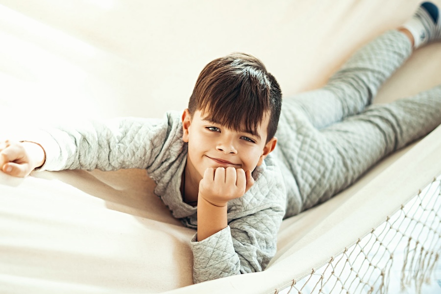 Image of a boy laying on a couch, smiling.