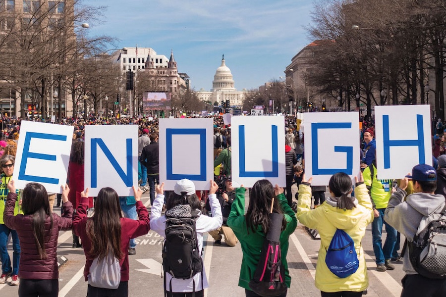 Image of 6 students holding up letters that spell Enough in front of the capitol