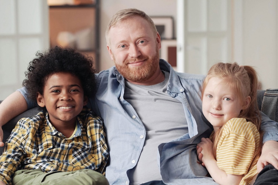 Image of a man hugging two kids