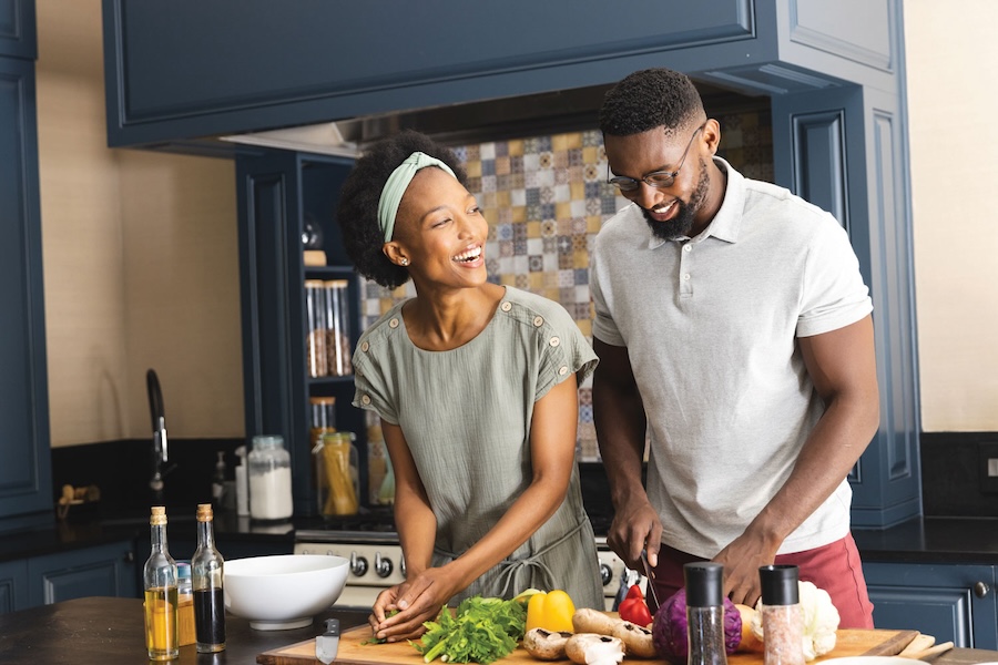 A young couple cooking together in a navy and tan kitchen