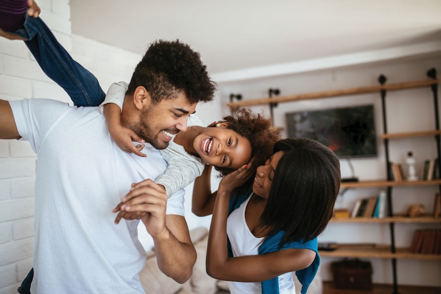 Image of parents holding up a child while they're laughing