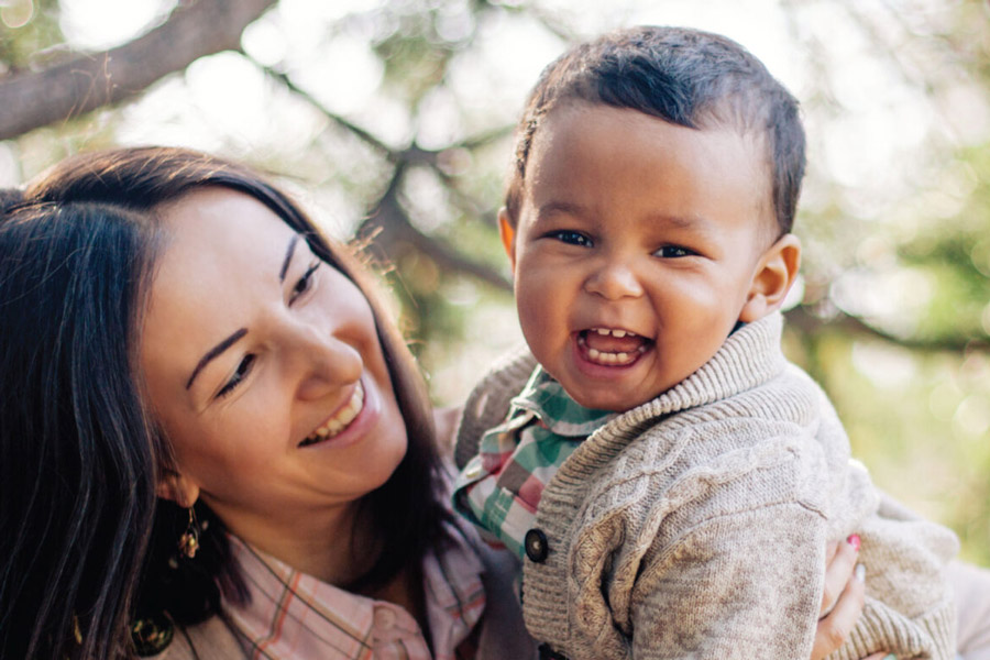 A woman holding a young baby who is smiling