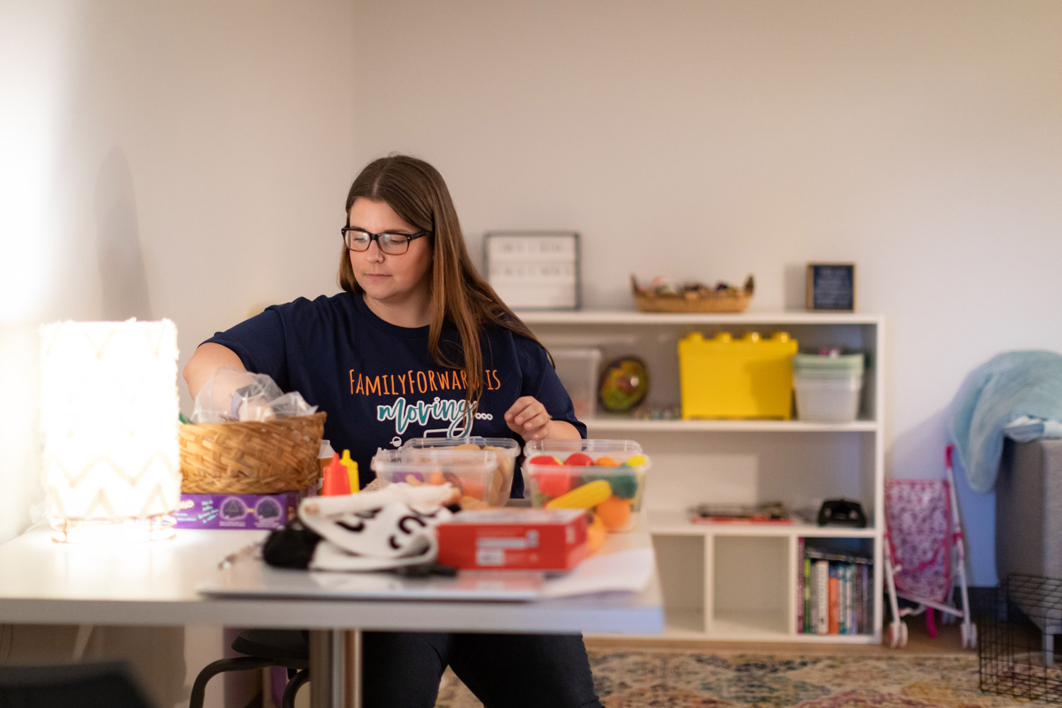 A FamilyForward employee sitting down while organizing supplies in a room.