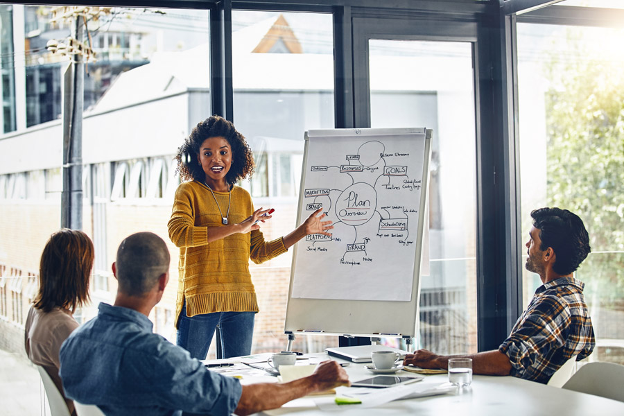 Woman and other workers brainstorm in boardroom, idea and strategy for planning in office.