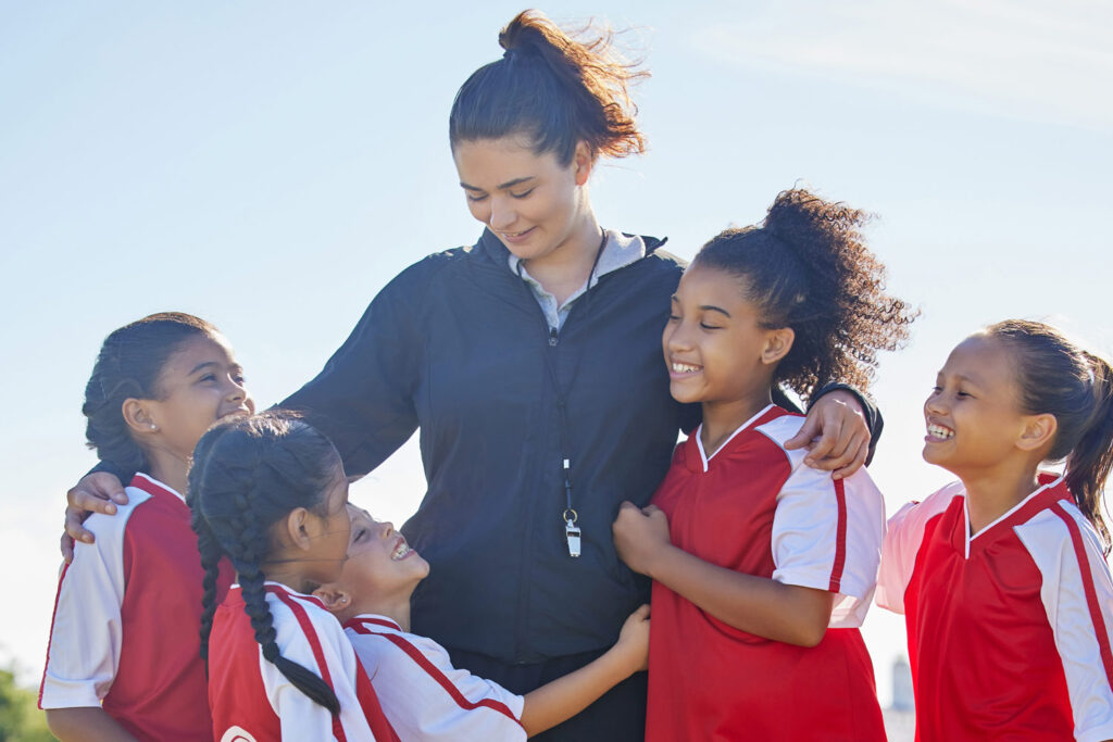 Female soccer coach hugging female players smiling