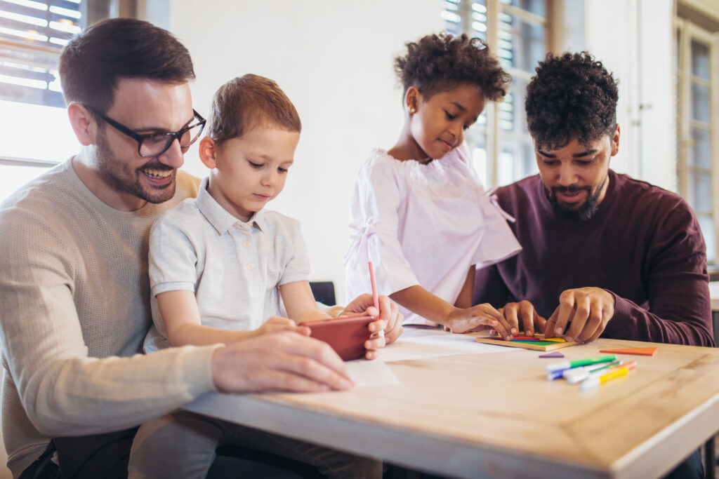 Two fathers playing educational games with their children.