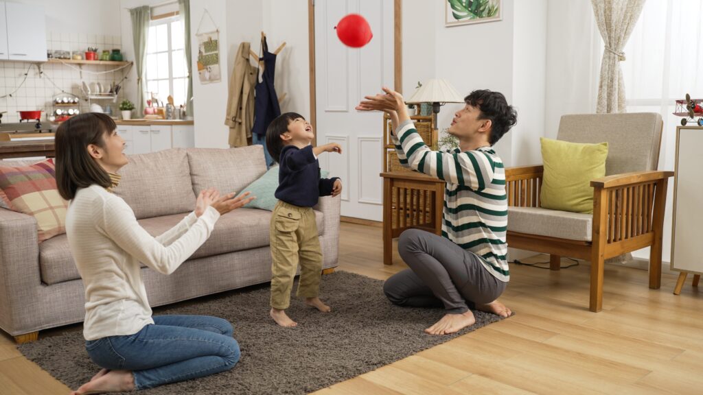 Cheerful parents playing with a balloon with their child