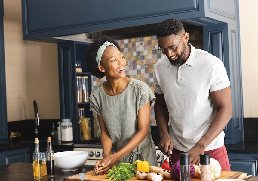 A young couple cooking together in a navy and tan kitchen