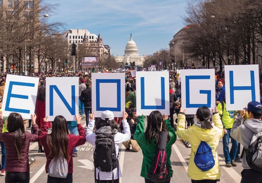 Image of 6 students holding up letters that spell Enough in front of the capitol