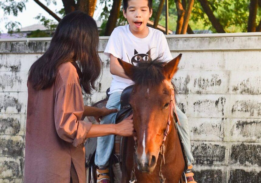 Image of a boy on a horse while a woman helps