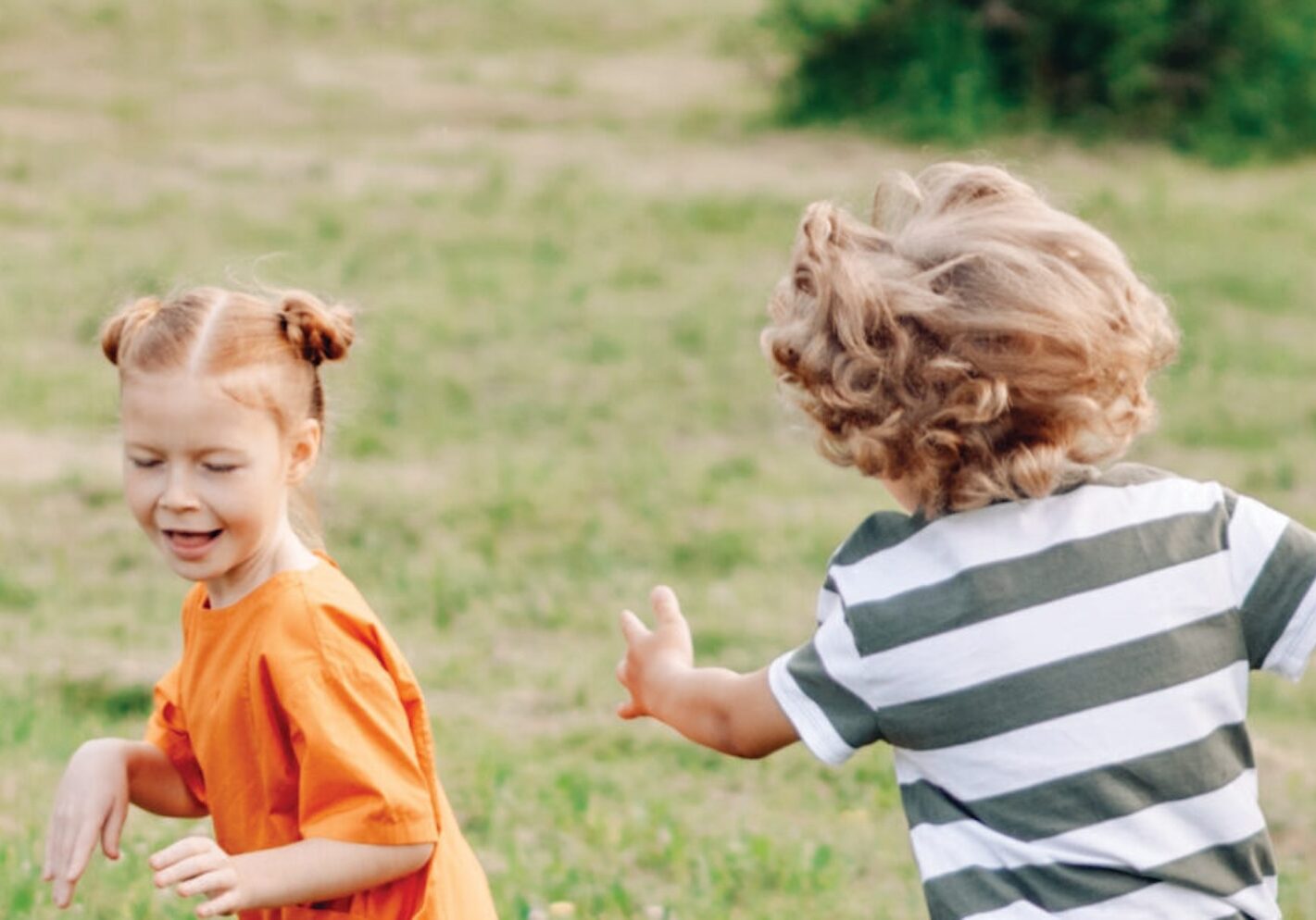 Image of a boy and a girl playing in a field