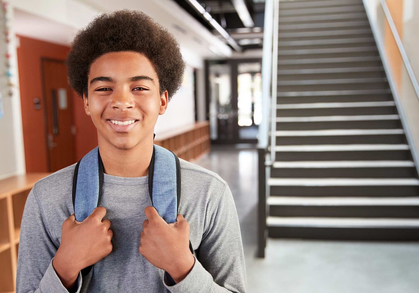 Image of a boy standing in a school with his backpack on