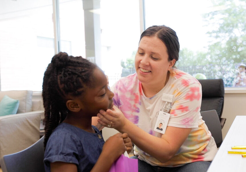 A FamilyForward staff member painting a young girl's face.