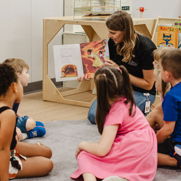 FamilyForward staff reading a book to a group of young children sitting in a circle.