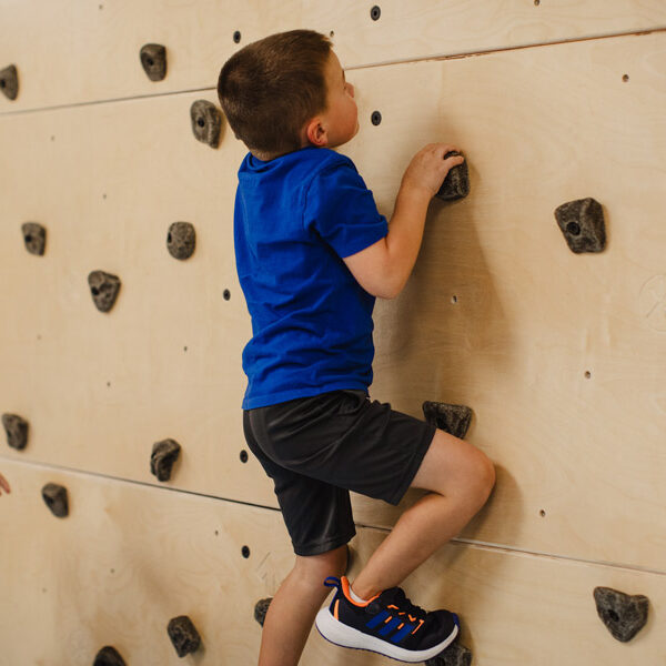 A young boy climbing a small rock wall at FamilyForward's Developmental Trauma Center.