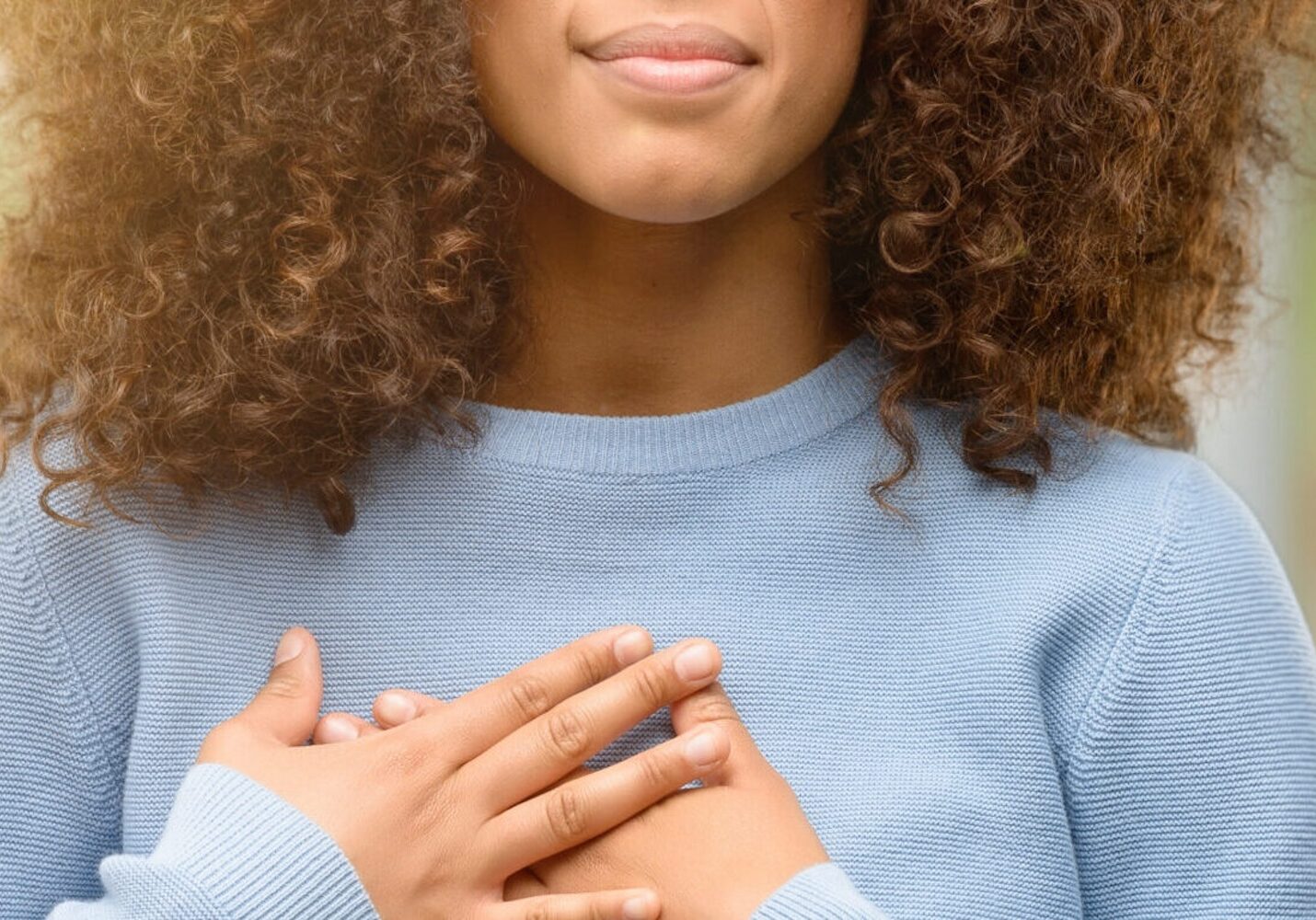 Image of African american woman wearing a sweater smiling with hands on chest with closed eyes and grateful gesture on face.