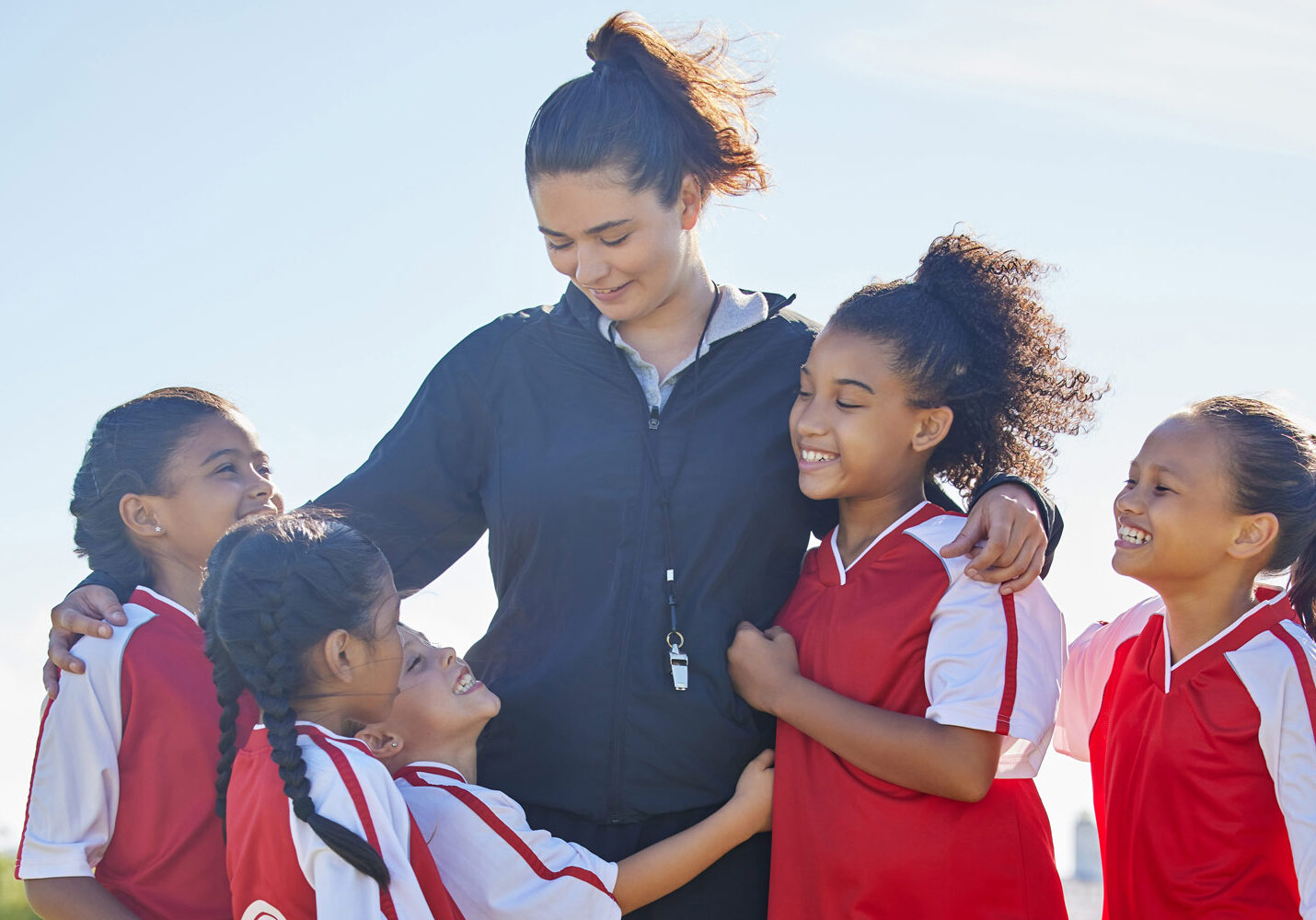 Female soccer coach hugging female players smiling