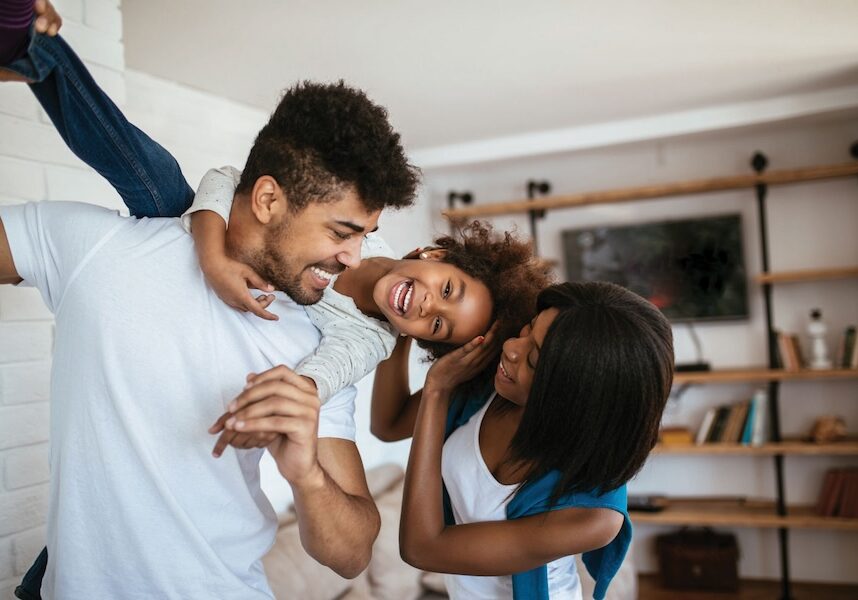 Image of parents holding up a child while they're laughing