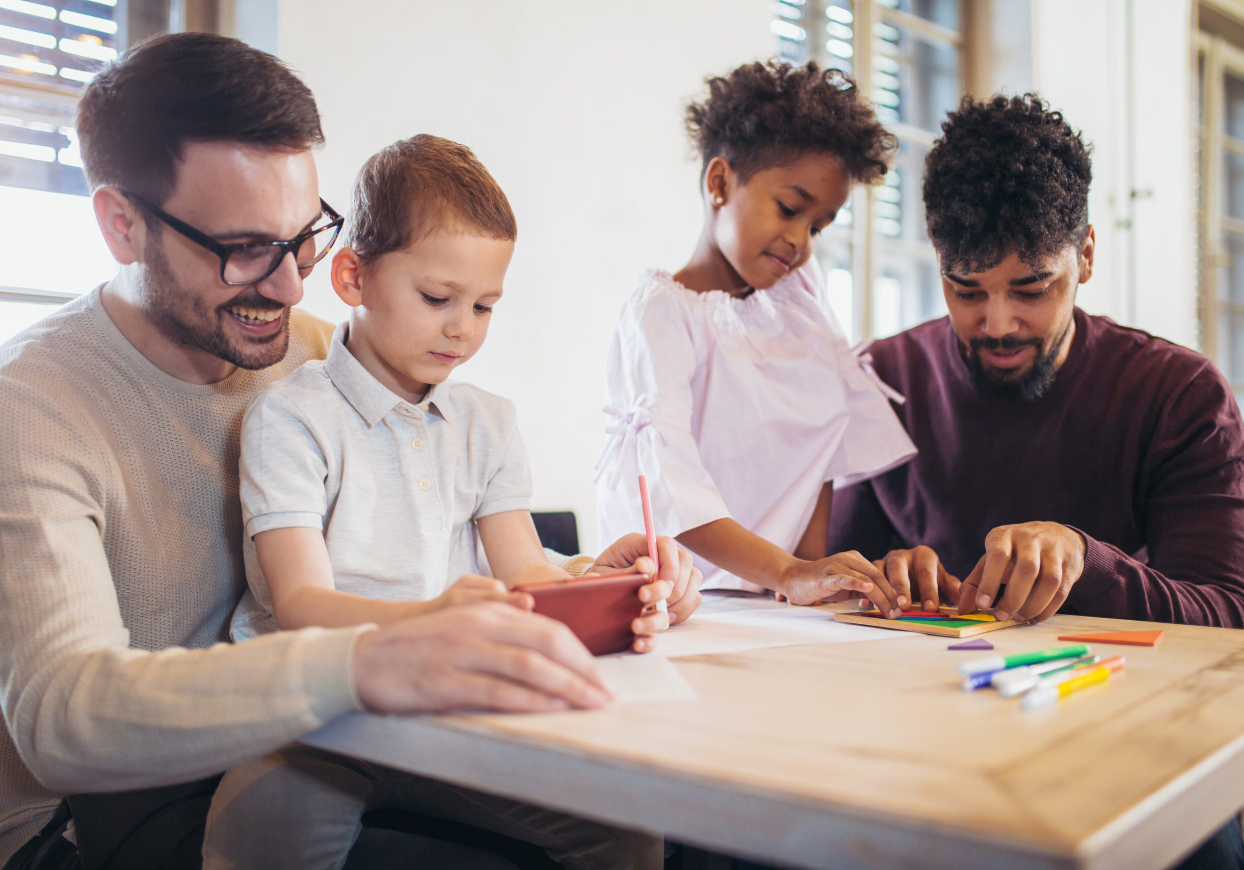 Two fathers playing educational games with their children.