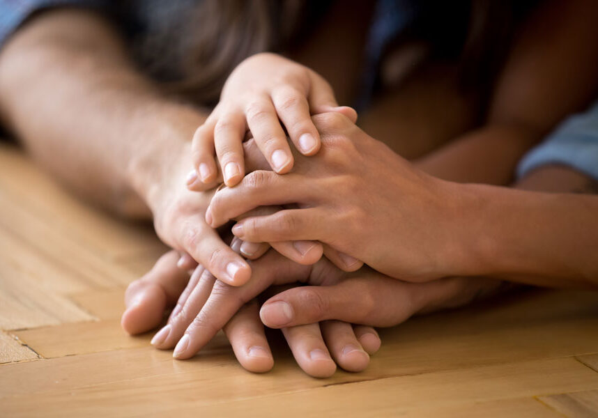 Close up of loving family stacking hands on a table.