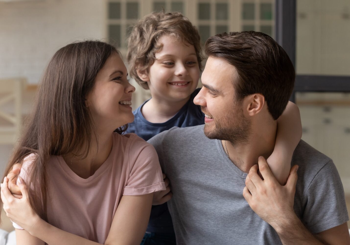 Image of parents holding their son over their shoulder