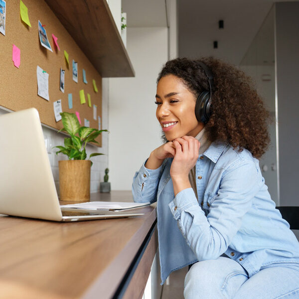 Young woman wearing headphones video calling on laptop.