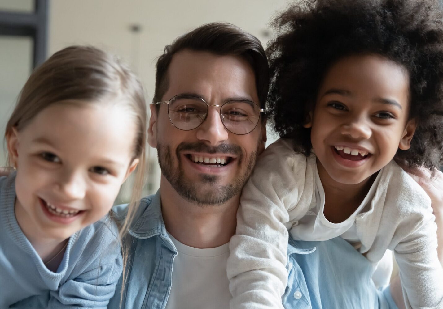 Image of two girls playing with their dad on his shoulders