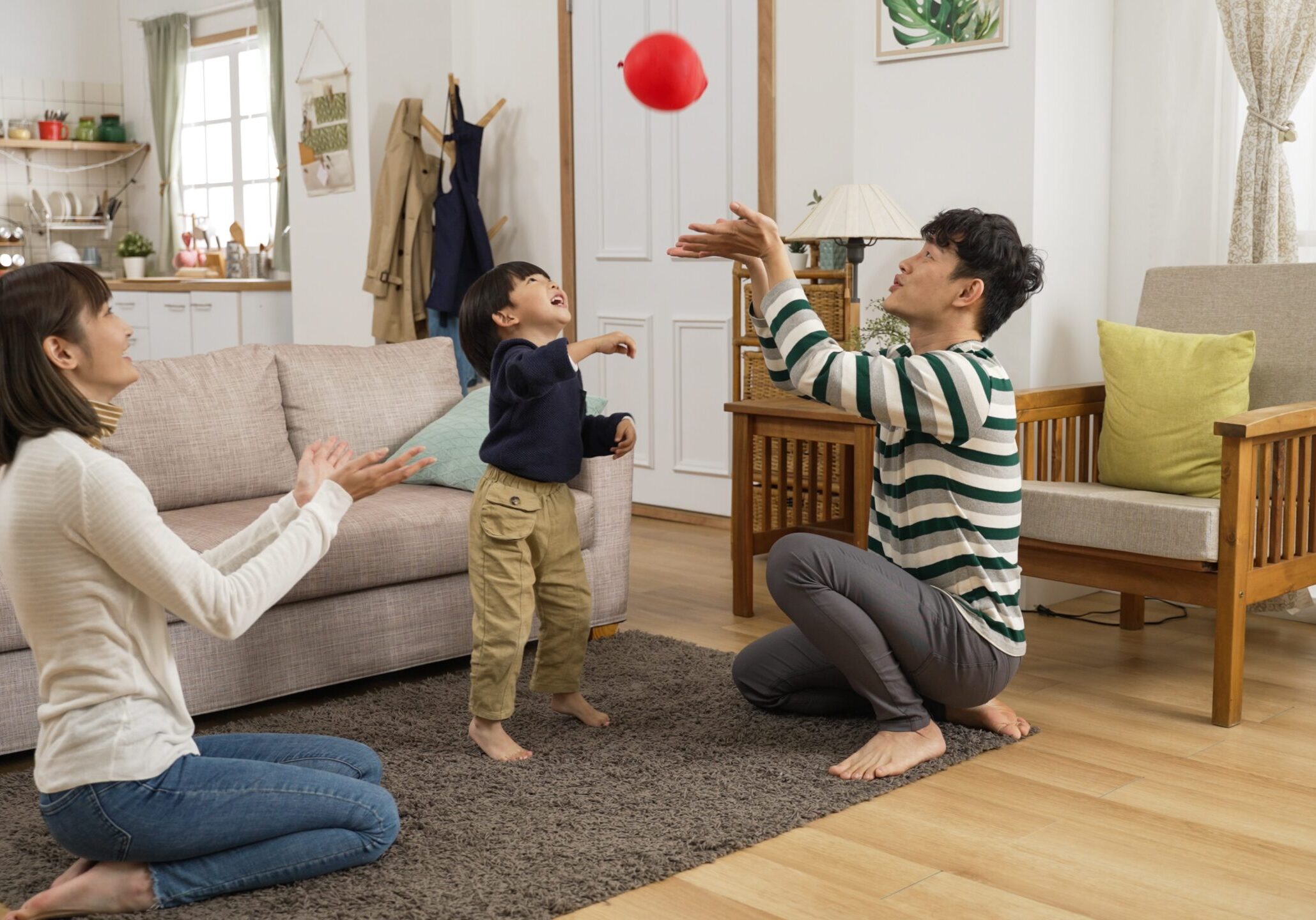 Cheerful parents playing with a balloon with their child