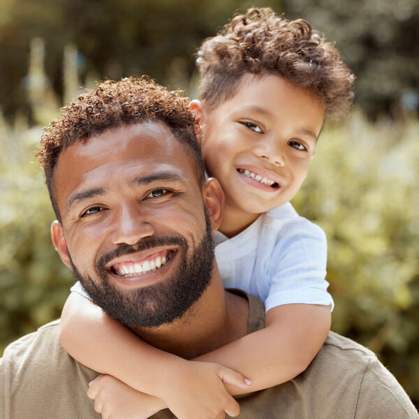 Happy father and boy smiling in a garden