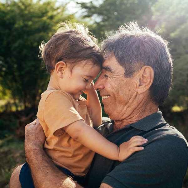 Playful grandfather spending time with his grandson in park on sunny day