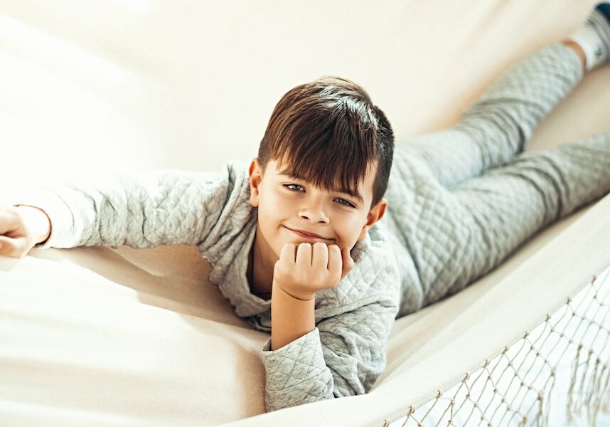 Image of a boy laying on a couch, smiling.